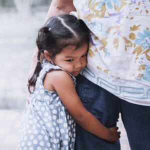 Sad asian little girl hugging her mother leg